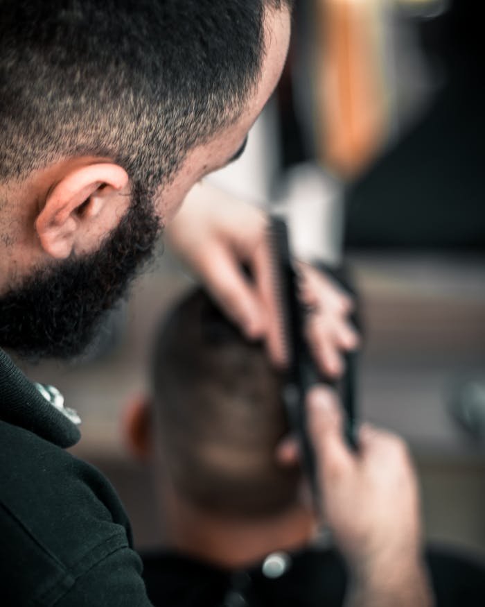 Close-up of a barber meticulously cutting a mans hair, focus on detail.